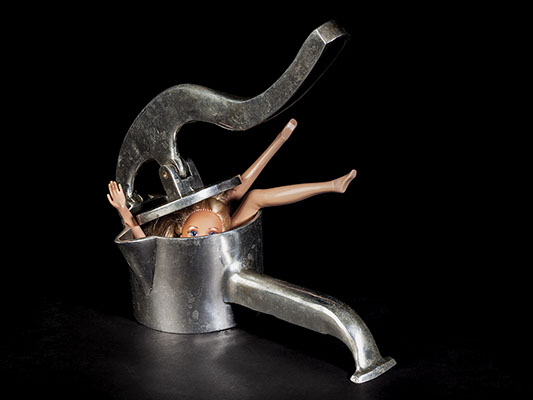 picture of Barbie crushed by a cooking utensil shot in studio Halet with a Mamiya medium format digital back Phase One