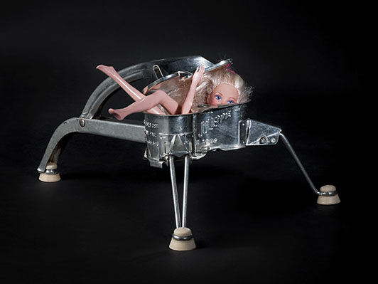 picture of Barbie crushed by a cooking utensil shot in studio Halet with a Mamiya medium format digital back Phase One