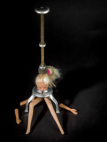 picture of Barbie crushed by a cooking utensil shot in studio Halet with a Mamiya medium format digital back Phase One