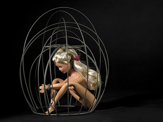 creative picture of Barbie chained in a cage shot in studio Halet with a Mamiya medium format digital back Phase One