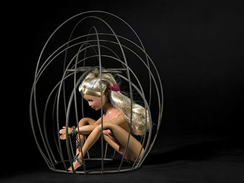 creative picture of Barbie chained in a cage shot in studio Halet with a Mamiya medium format digital back Phase One
