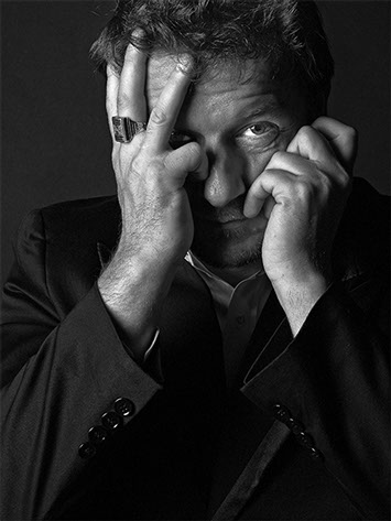 close portrait in black and white of a Massimo man holding his head in the hands discovering a look between her finger shot in studio Halet